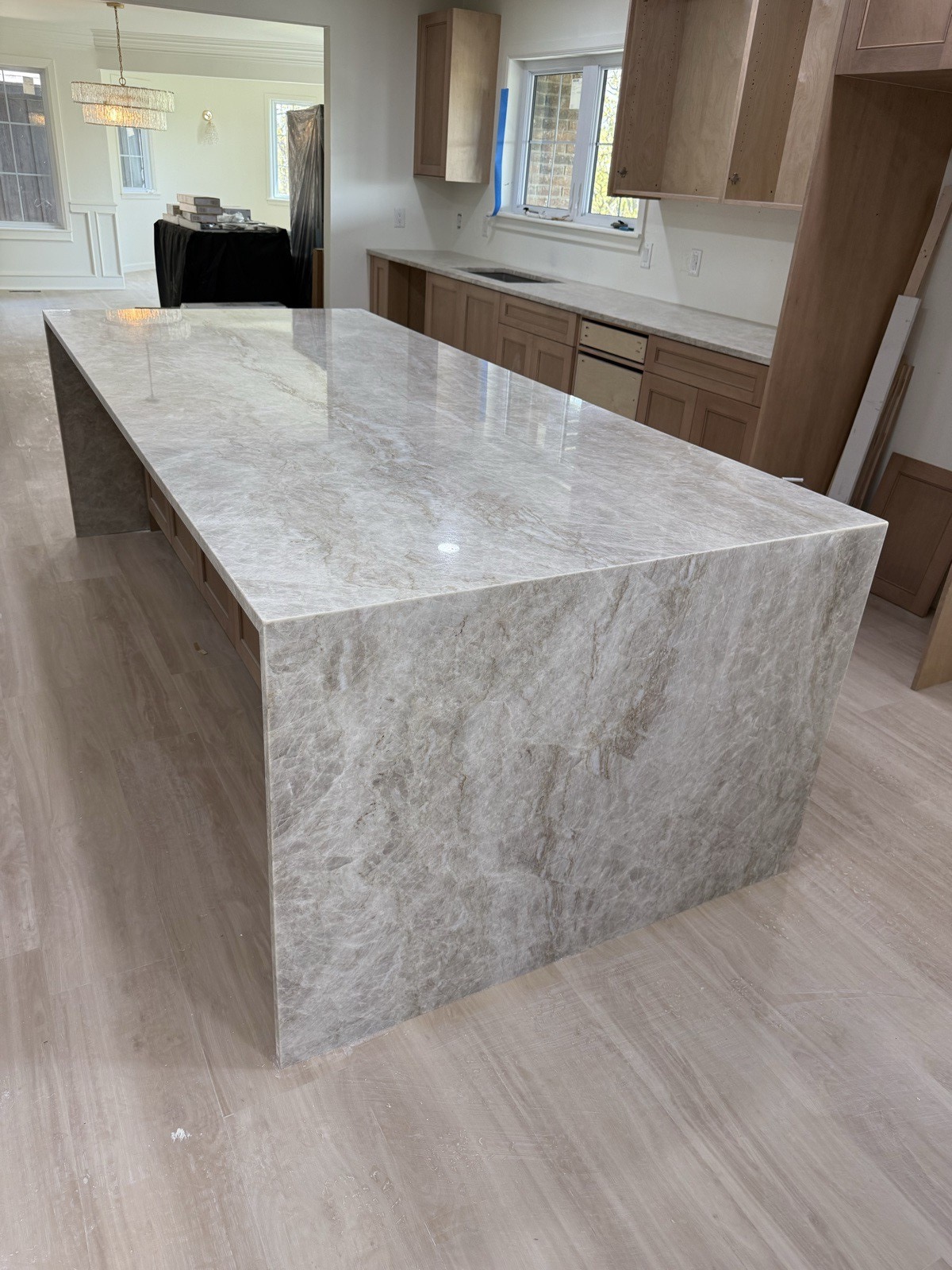 Finished kitchen with a cream quartzite waterfall island and light wood cabinetry
